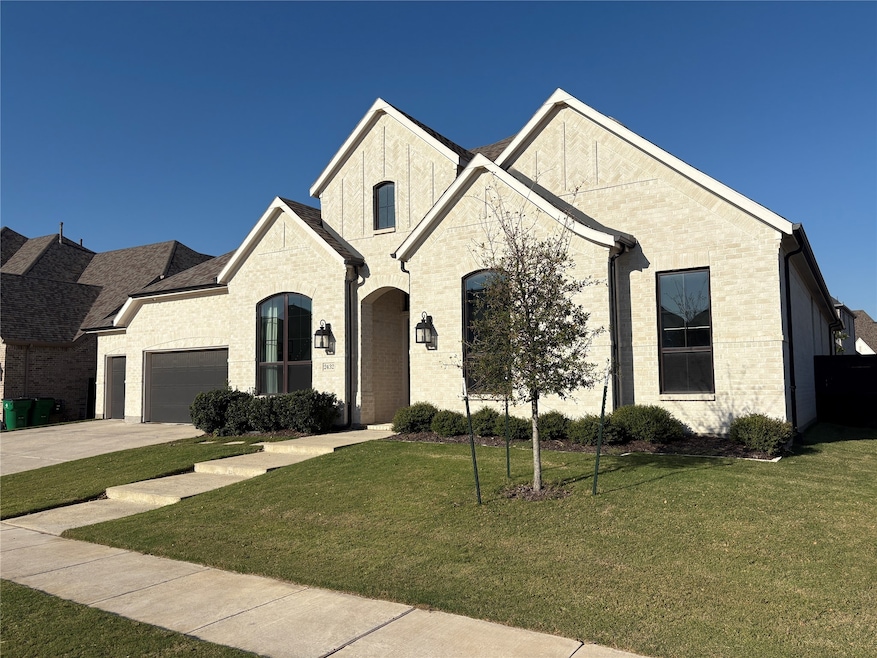 French country home featuring brick siding, driveway, a front lawn, and an attached garage