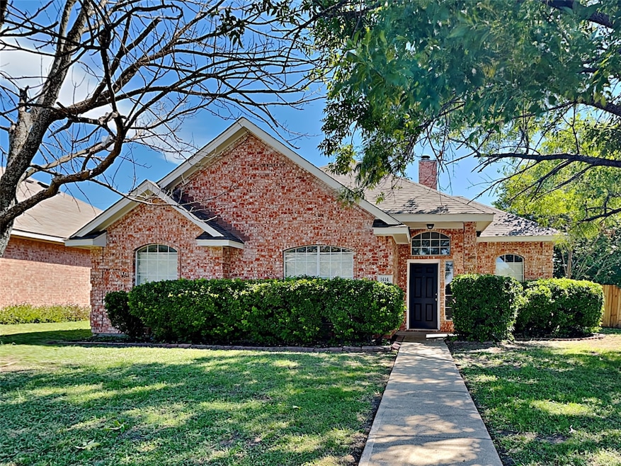 View of front facade featuring a front lawn, a chimney, and brick siding