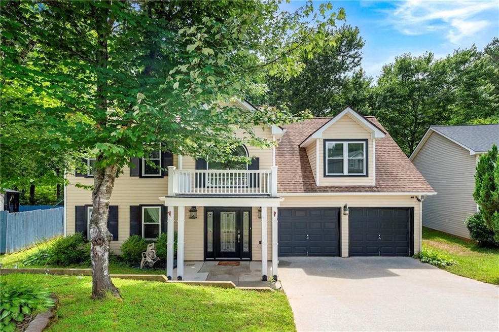 View of front of property with concrete driveway, a balcony, french doors, and roof with shingles