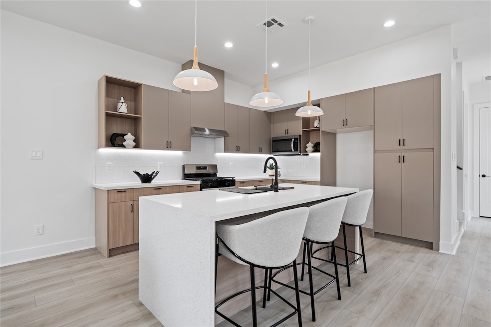 The kitchen is a showpiece of both beauty and function, featuring abundant cabinetry and thoughtful storage throughout. An oversized quartz waterfall island anchors the space, offering the perfect spot for cooking, gathering, and creating lasting memories. It’s a true heart of the home designed for modern living.