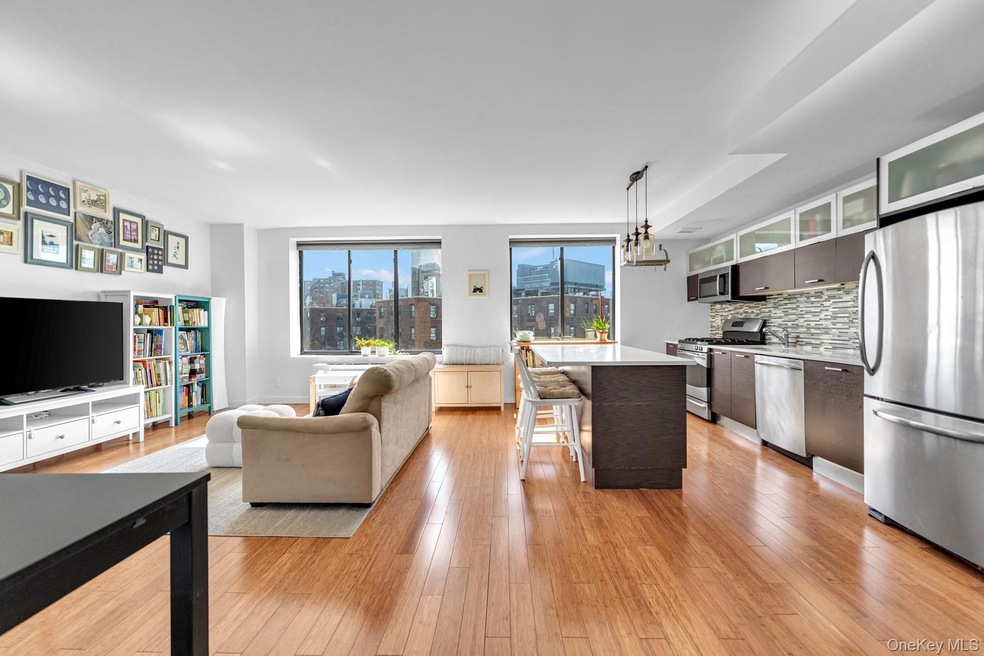 Kitchen with stainless steel appliances, pendant lighting, light wood finished floors, open floor plan, and decorative backsplash