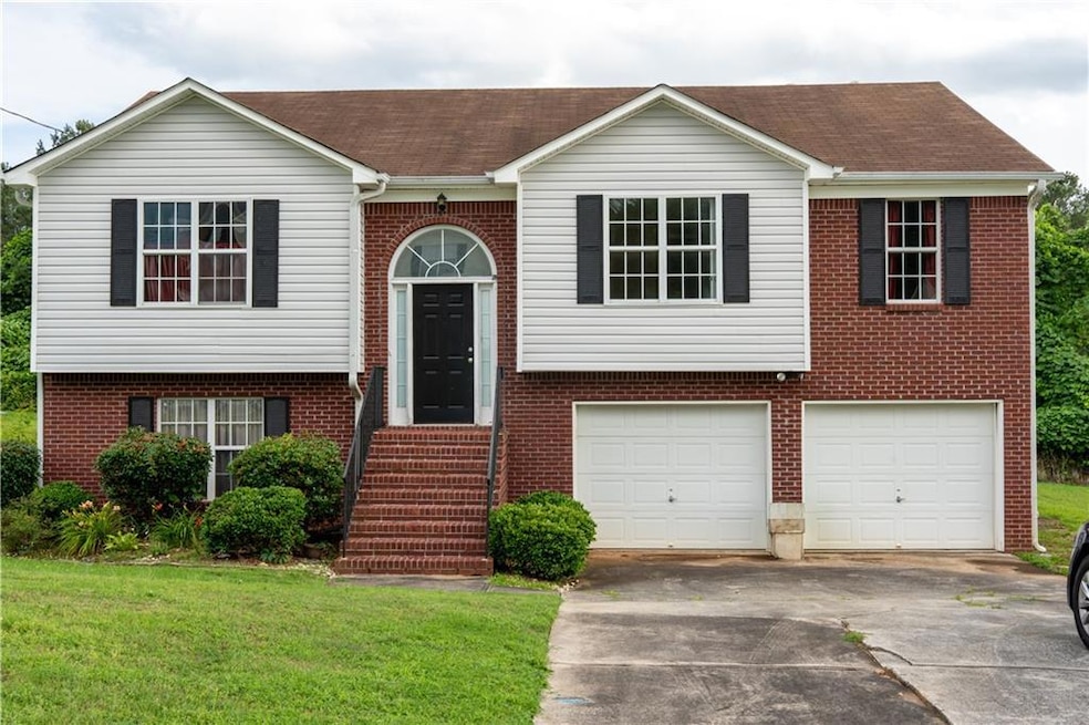 Raised ranch with driveway, a garage, brick siding, a front yard, and a shingled roof