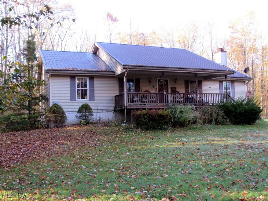View of front of home with a chimney, covered porch, and a front lawn