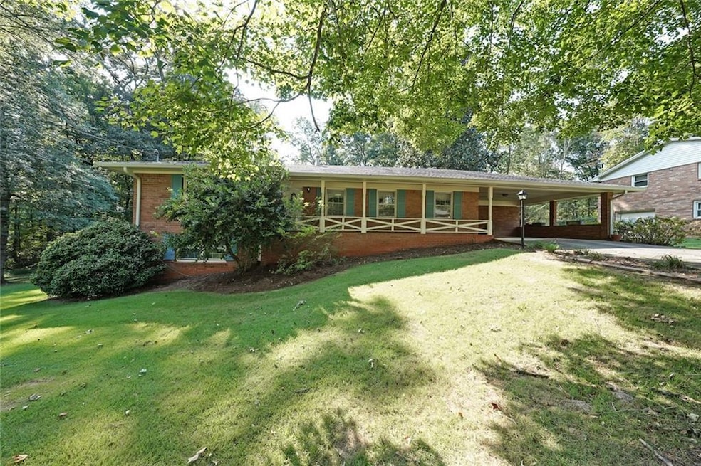 View of front of home featuring brick siding, a carport, a front lawn, and concrete driveway