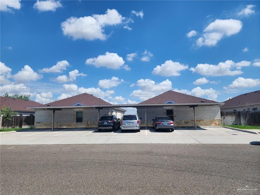 View of front of property with covered and uncovered parking and brick siding