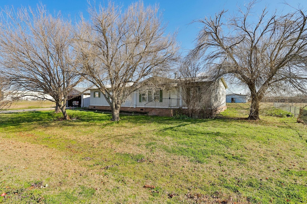 View from the front of the home with the side carport and the workshop in the background.