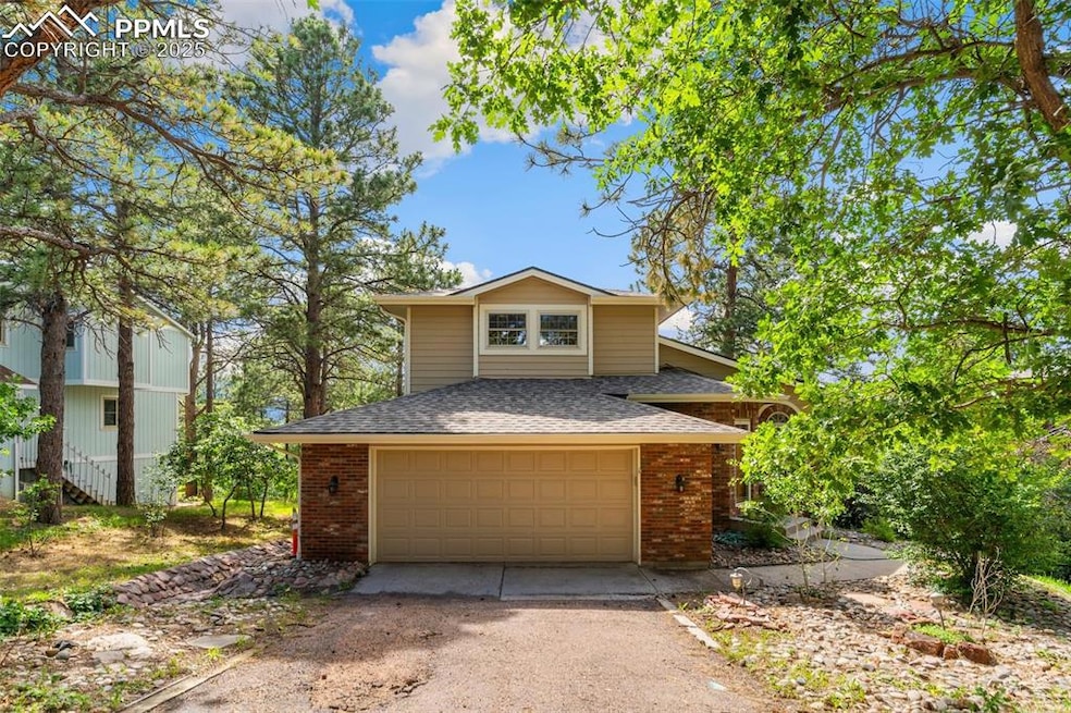 View of front of home with a shingled roof, dirt driveway, brick siding, and a garage