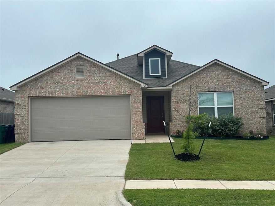 View of front of property with brick siding, driveway, a front lawn, and roof with shingles