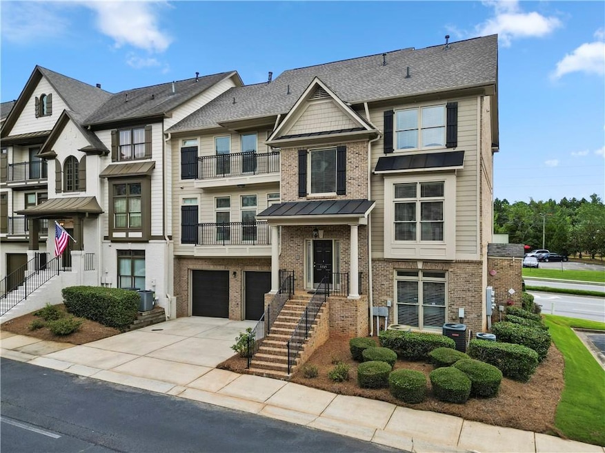 Townhome / multi-family property featuring brick siding, concrete driveway, an attached garage, and a balcony