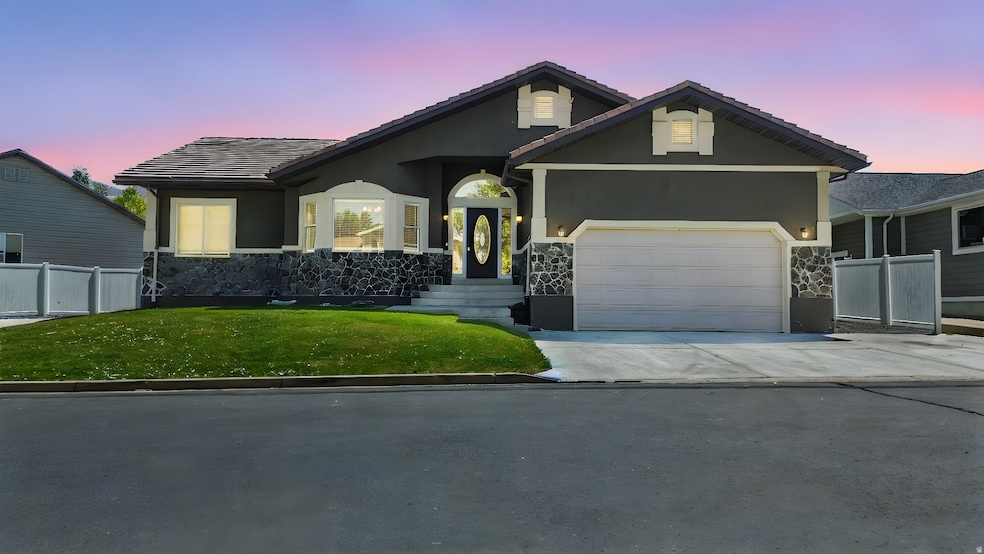 View of front of house featuring stone siding, driveway, a garage, stucco siding, and a tile roof