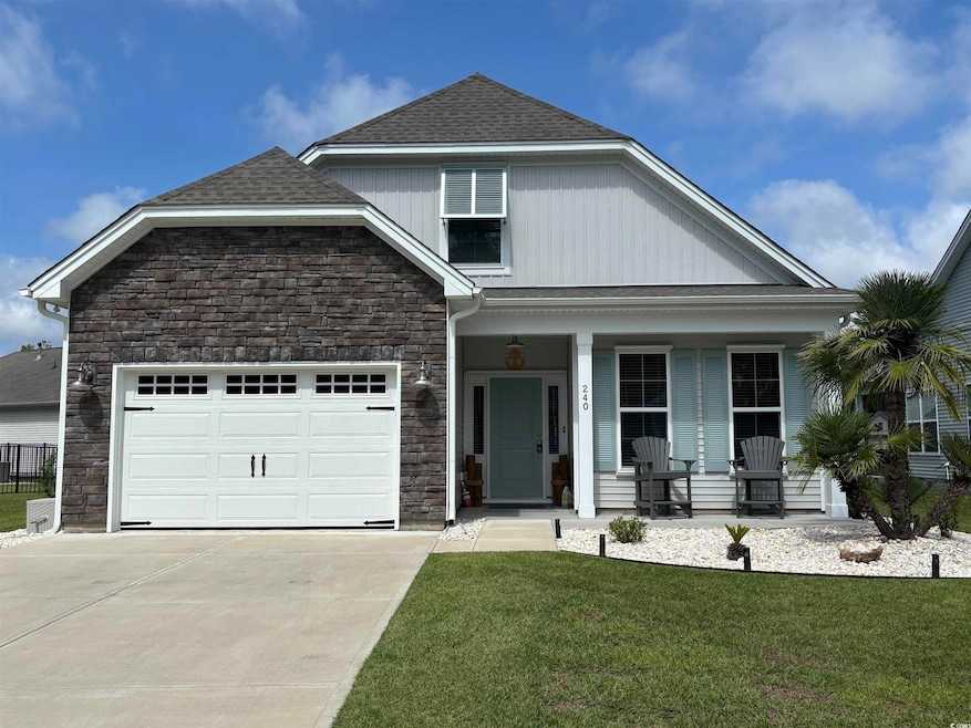 View of front of property featuring stone siding, covered porch, concrete driveway, and a front lawn