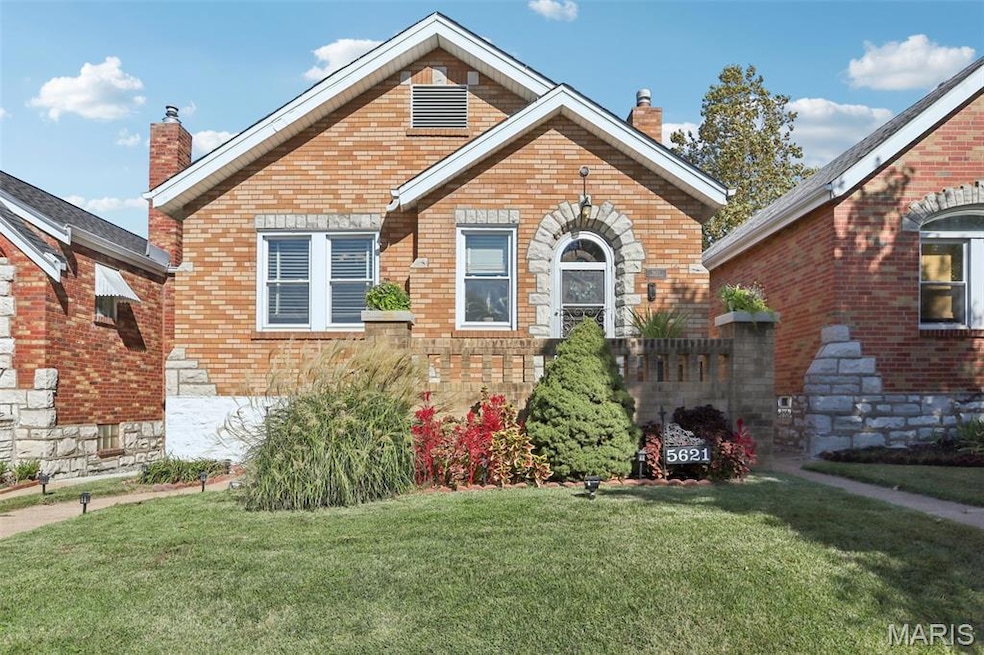 View of front of property with a chimney, a front yard, and brick siding