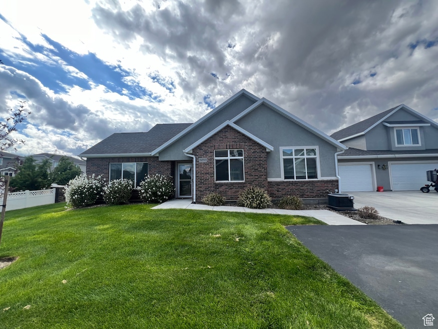 View of front of house featuring brick siding, driveway, a garage, and stucco siding