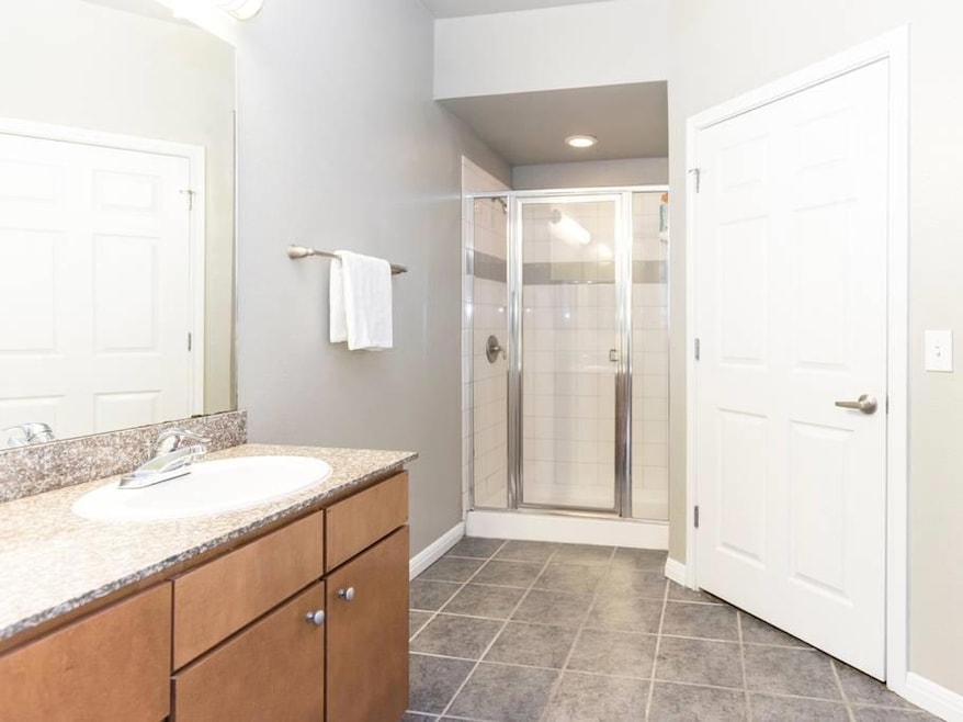 Full bath featuring vanity, a stall shower, and dark tile patterned floors