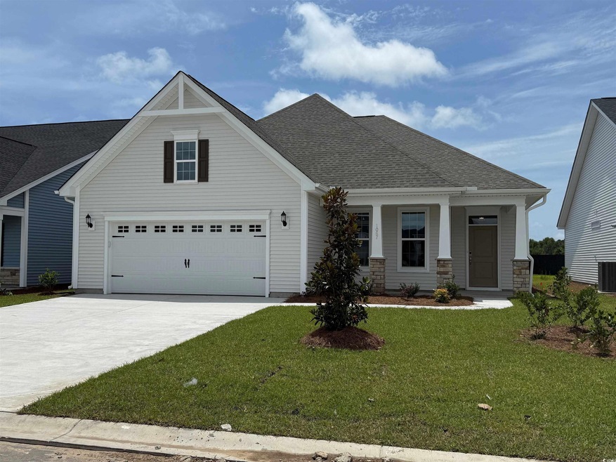 View of front facade with driveway, a front yard, a porch, and roof with shingles