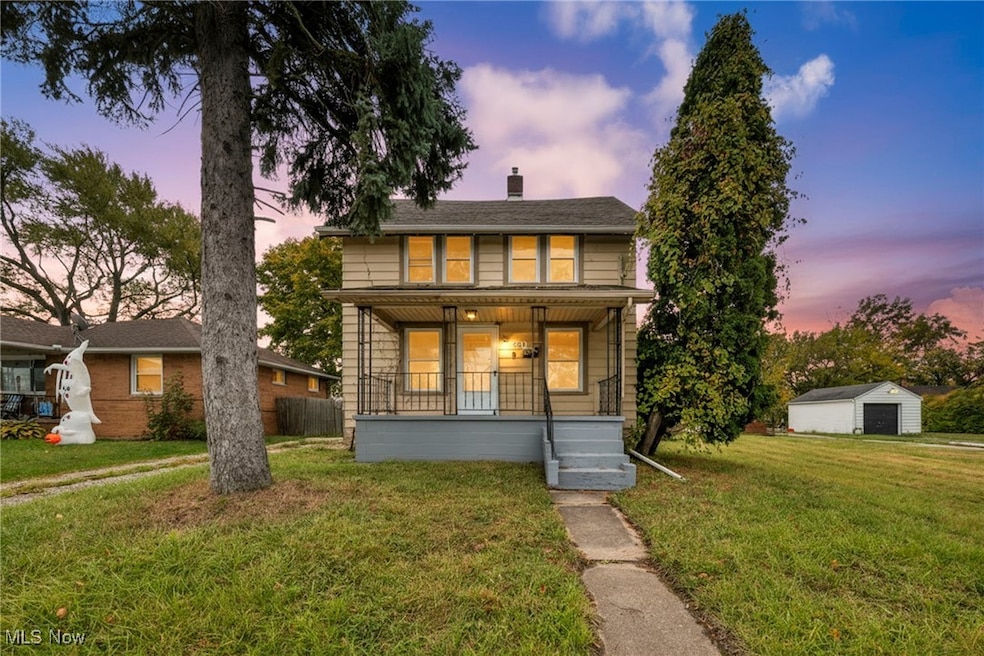 View of front of house with covered porch, a front yard, a chimney, and an outbuilding
