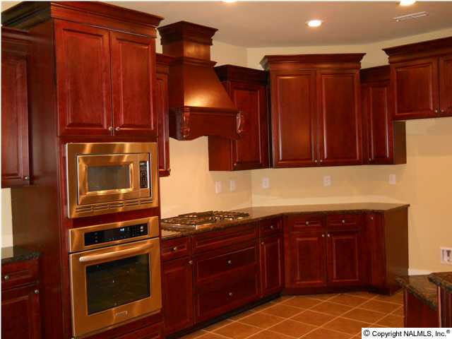 FULL OVERLAY SOFT CLOSE CABINETS WITH TUMBLED STONE BACKSPLASH, GRANITE COUNTERTOPS, KITCHEN AID STAINLESS APPLIANCES, GAS COOKTOP, DECORATIVE DIRECT VENT RANGE HOOD, 5
