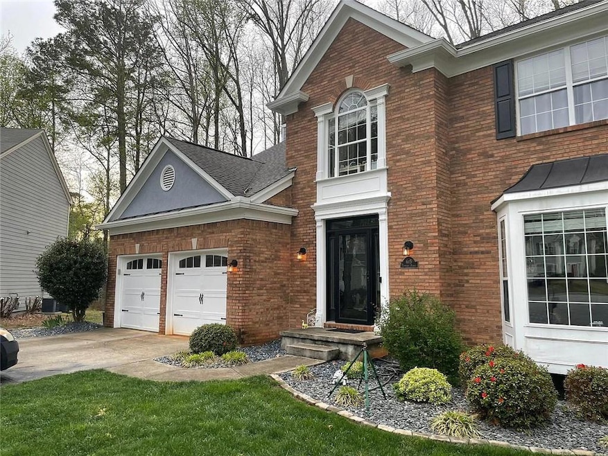 View of front facade with brick siding, concrete driveway, and a garage