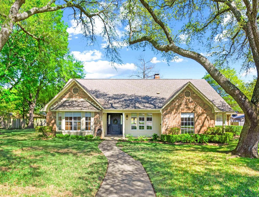 View of front facade with roof with shingles, a chimney, a front lawn, and brick siding