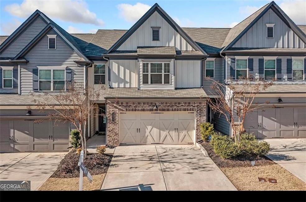 View of front facade featuring an attached garage, concrete driveway, board and batten siding, and brick siding