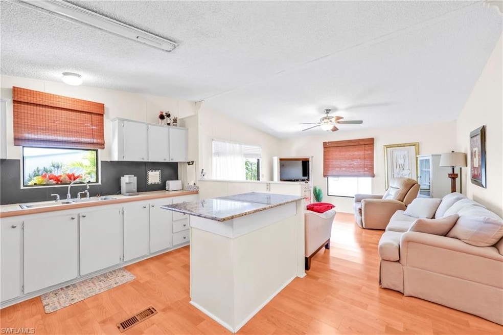 Kitchen with visible vents, light wood-type flooring, lofted ceiling, a sink, and open floor plan