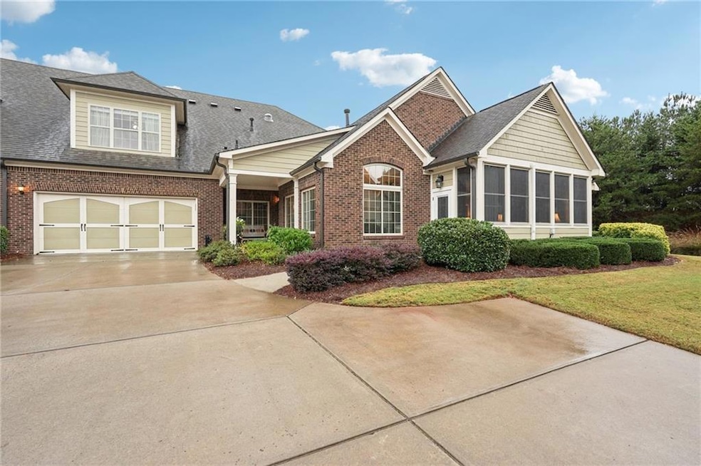 View of front of home featuring brick siding, a sunroom, roof with shingles, driveway, and a front yard