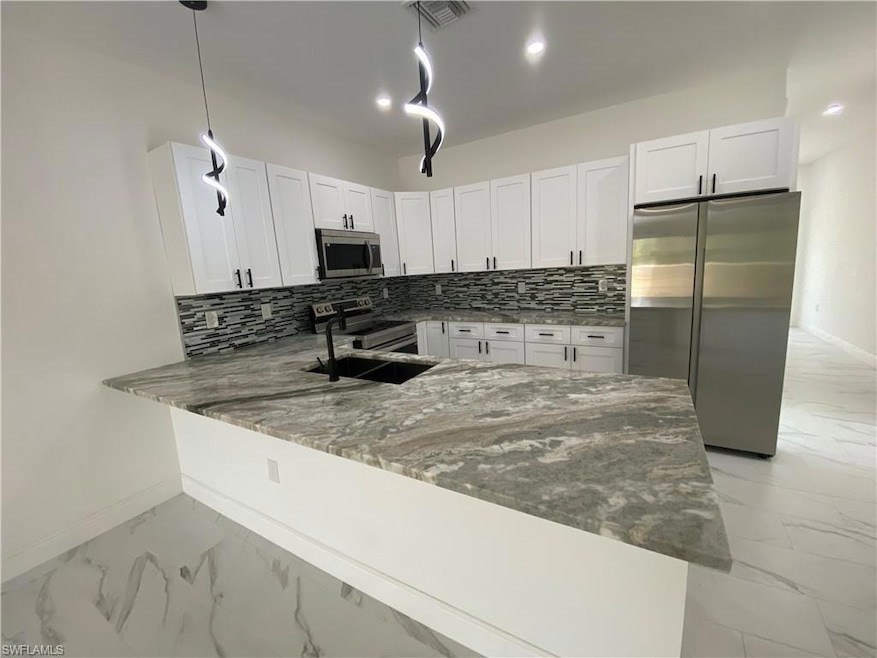 Kitchen featuring stainless steel appliances, marble finish floor, and stone counters