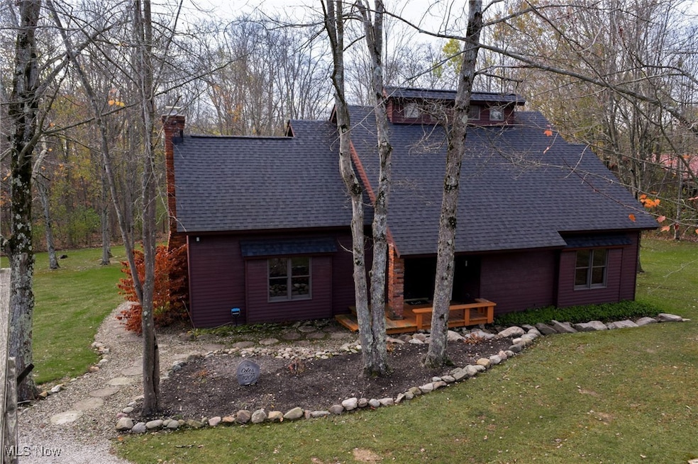 View of front of property with a front yard, roof with shingles, a wooden deck, and a chimney