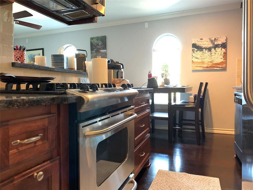 Kitchen with crown molding, ceiling fan, dark woo