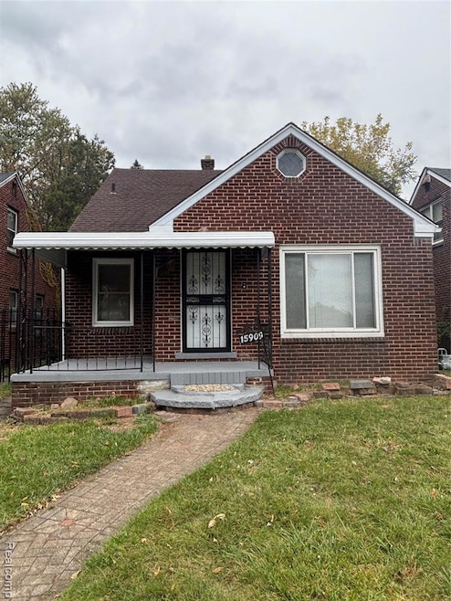 Bungalow-style house featuring a front lawn, covered porch, brick siding, and a chimney