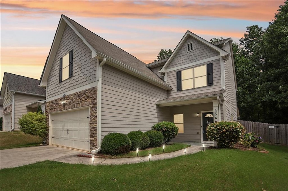 Traditional-style home featuring an attached garage, driveway, and stone siding