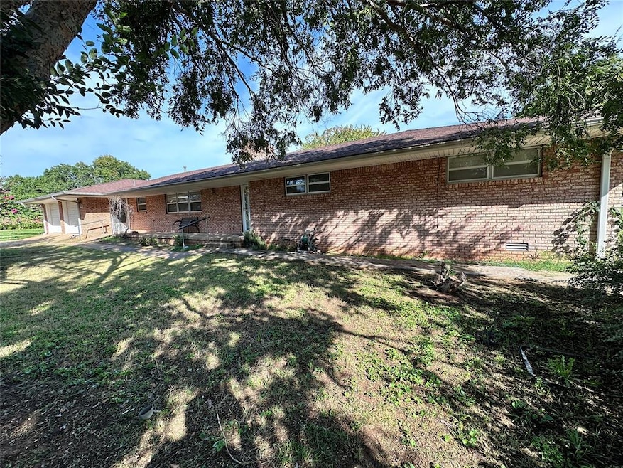 Rear view of property with crawl space, brick siding, and a lawn
