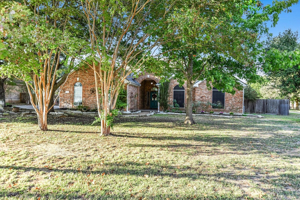 View of property hidden behind natural elements featuring brick siding