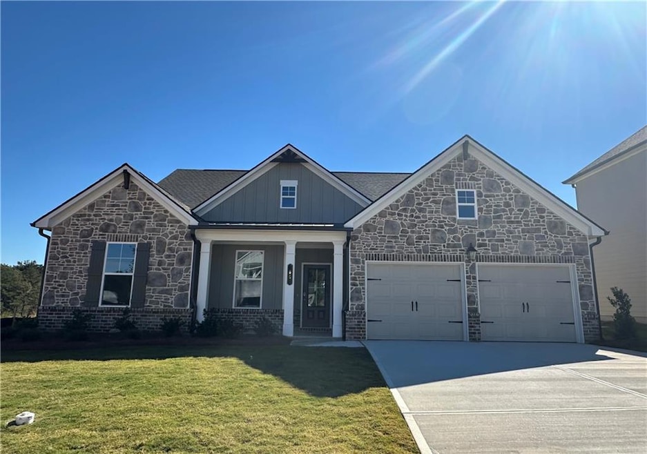Craftsman house featuring a porch, a front yard, concrete driveway, board and batten siding, and stone siding