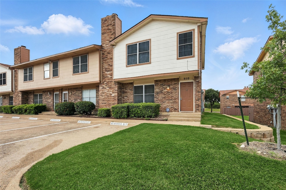 View of property with a chimney, a front yard, uncovered parking, brick siding, and entry steps