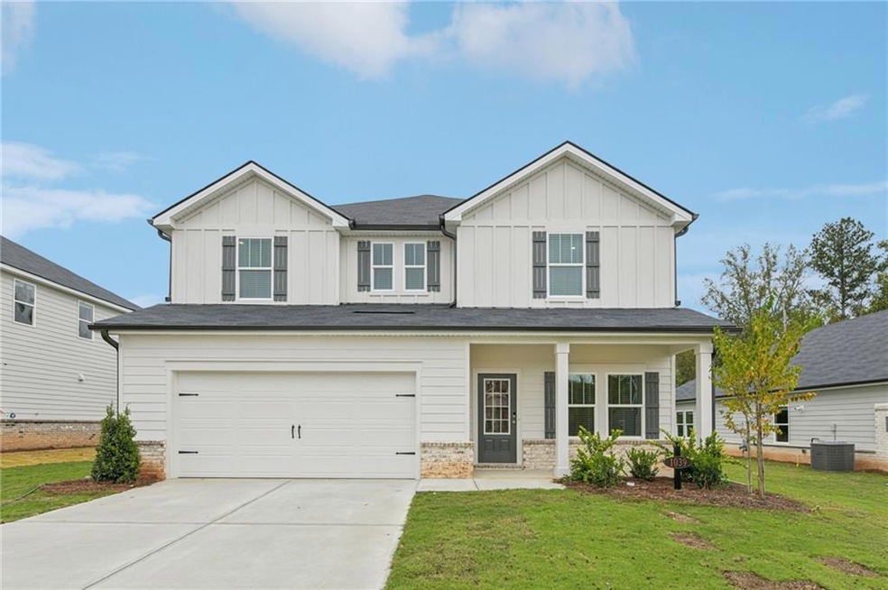 View of front of house with board and batten siding, a garage, covered porch, a front yard, and driveway