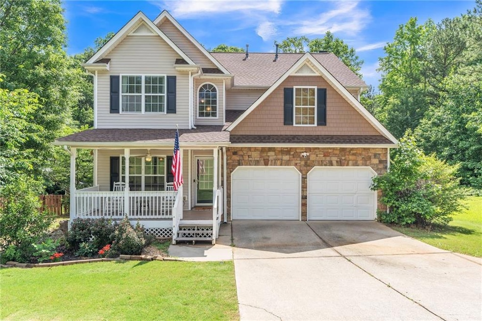 View of front facade with a porch, concrete driveway, a front yard, and a shingled roof