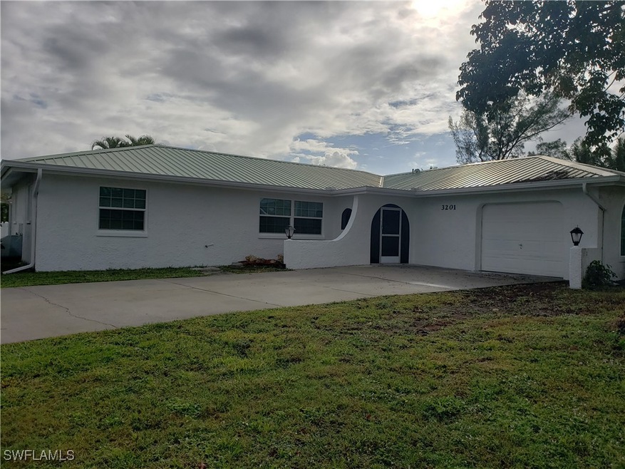 Ranch-style home with an attached garage, a front yard, metal roof, and stucco siding