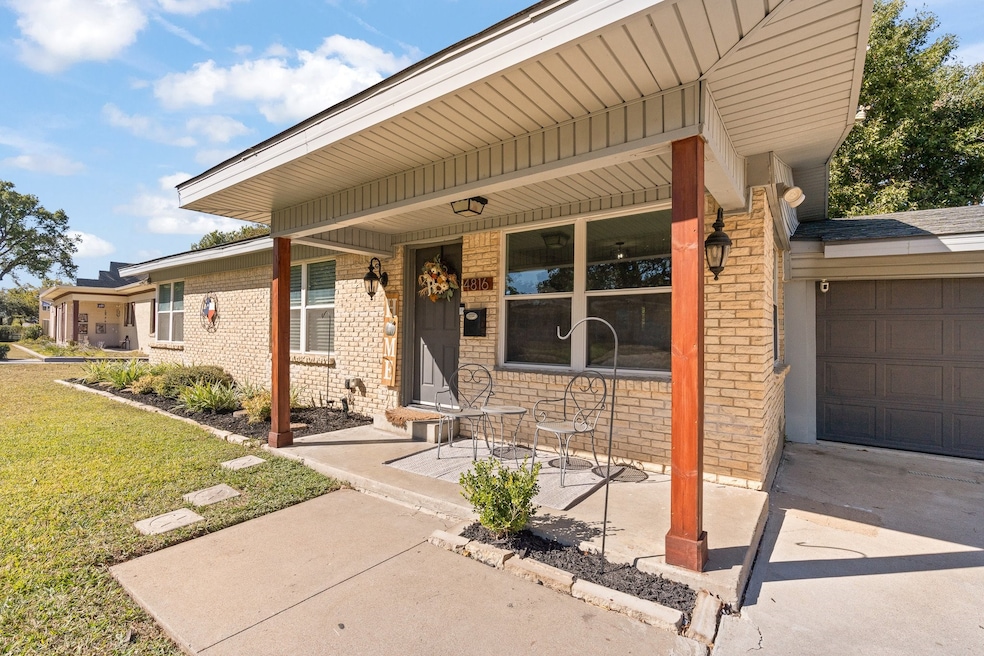 Doorway to property featuring covered porch, brick siding, and a yard
