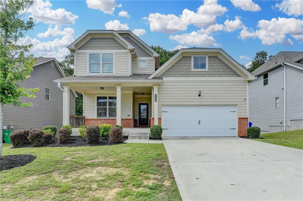Craftsman-style home featuring brick siding, covered porch, and a front yard