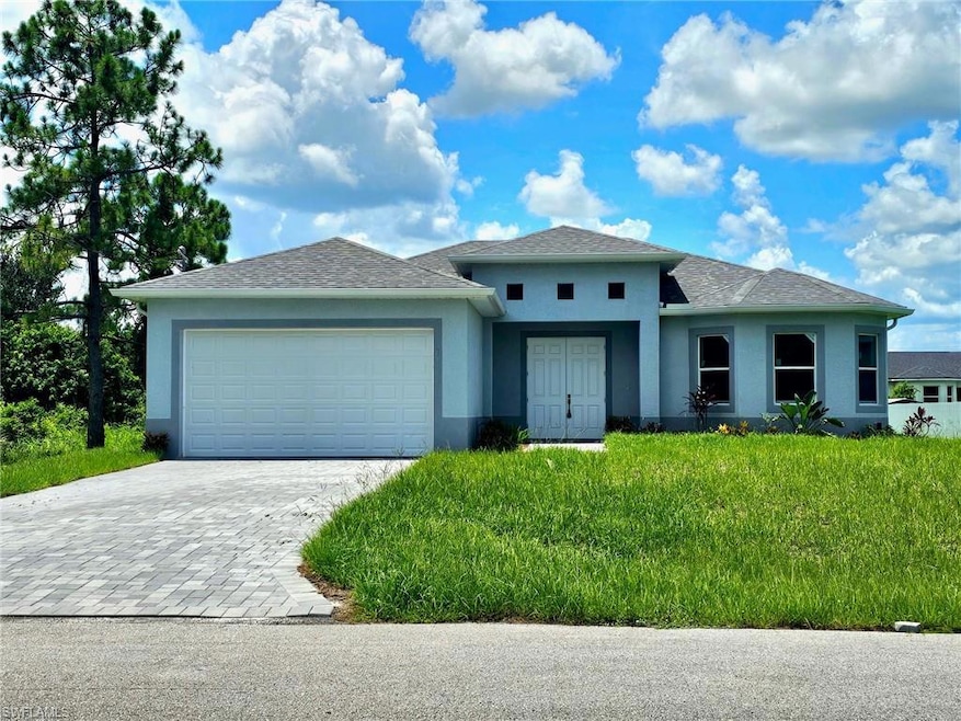 Prairie-style house with stucco siding, decorative driveway, an attached garage, and a shingled roof