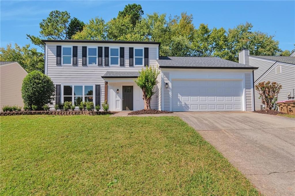View of front of home with a garage and a front ya