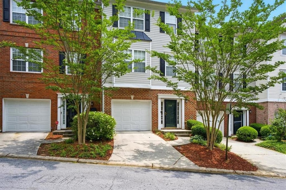 Multi unit property featuring an attached garage, concrete driveway, and brick siding
