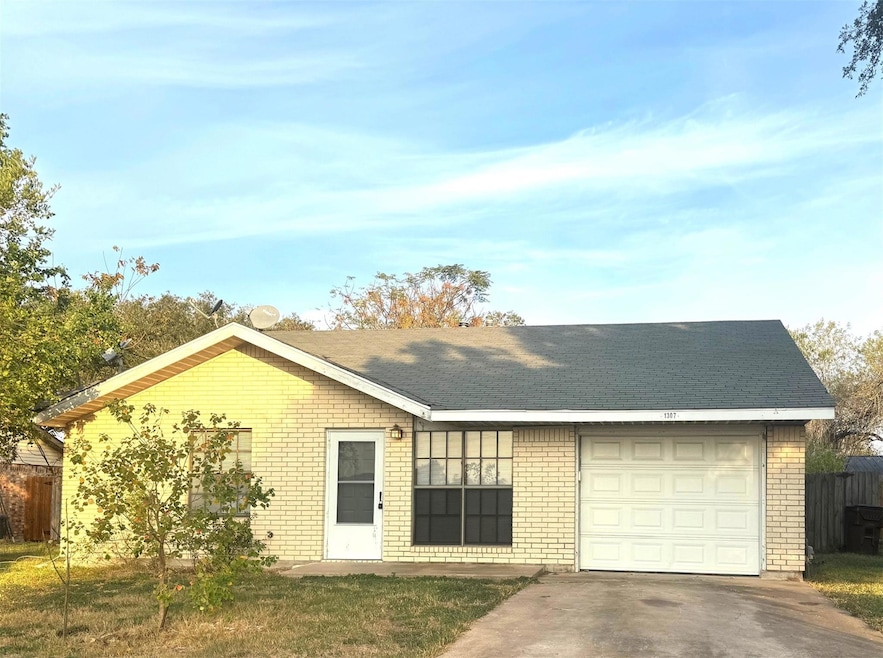 Ranch-style home featuring concrete driveway, brick siding, a shingled roof, and a garage