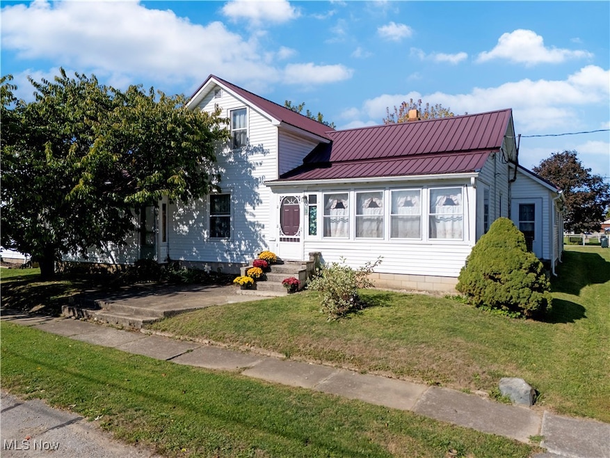 View of front of property with a metal roof and a front lawn