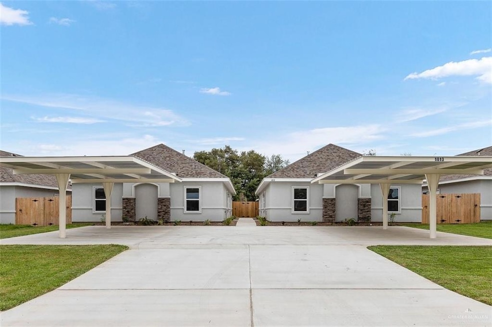 View of front facade featuring stucco siding, concrete driveway, a front yard, and fence
