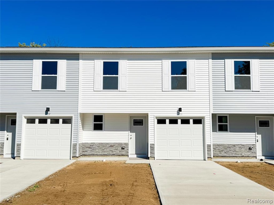 View of front of property with stone siding, concrete driveway, a garage, and covered porch