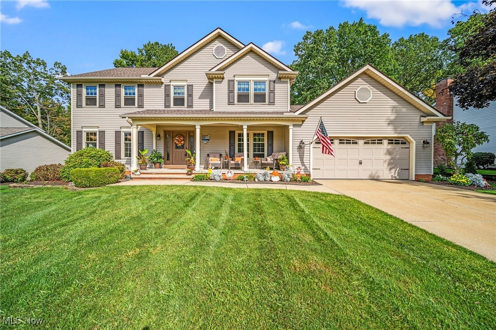 View of front of house with covered porch, a garage, concrete driveway, and a front yard