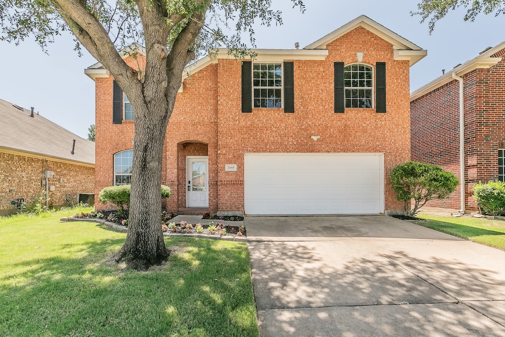 Traditional home with a front lawn, driveway, brick siding, and a garage