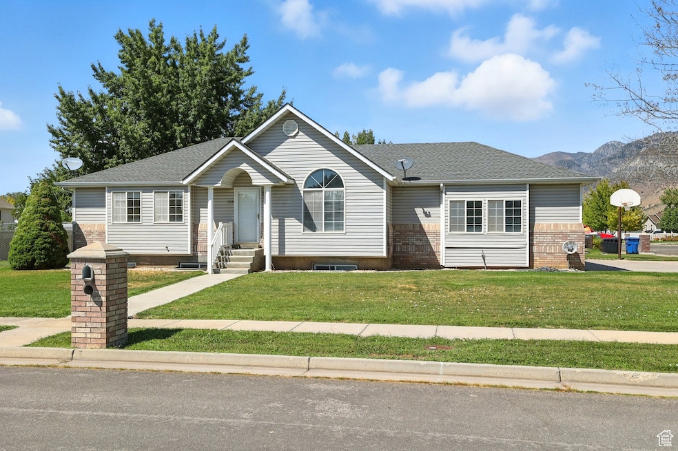 Ranch-style home with a front yard, a shingled roof, and a mountain view